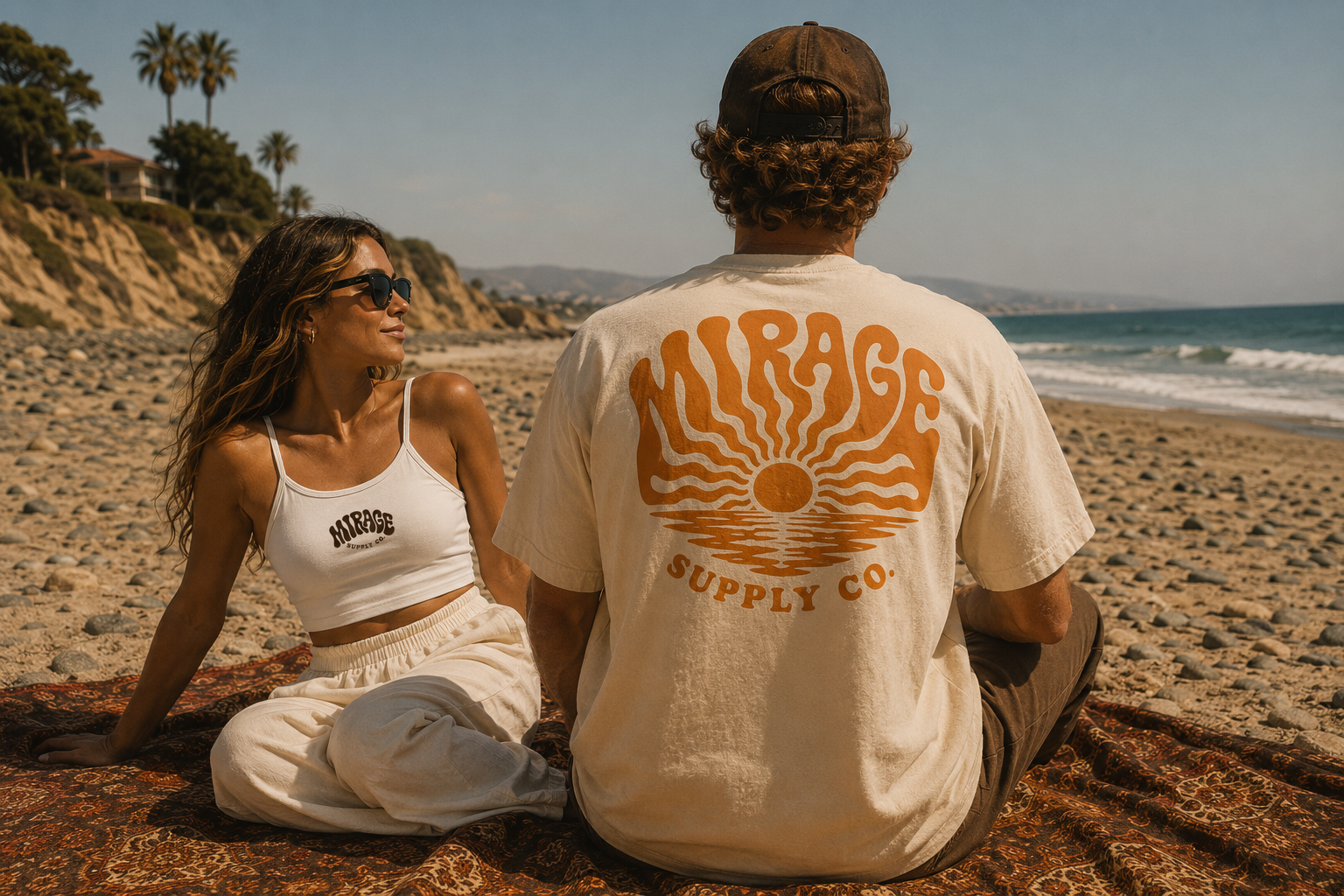 Two friends on a beach blanket at golden hour wearing Mirage Supply Co. apparel